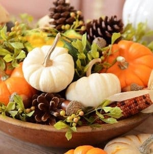 mini pumpkins, pinecones and greenery in a wooden bowl