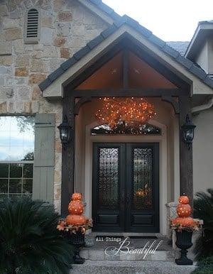 Fall Porch Lighting with pumpkin topiaries next to the front door