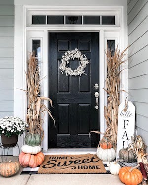 pumpkins and dried corn stalks on either side of the door